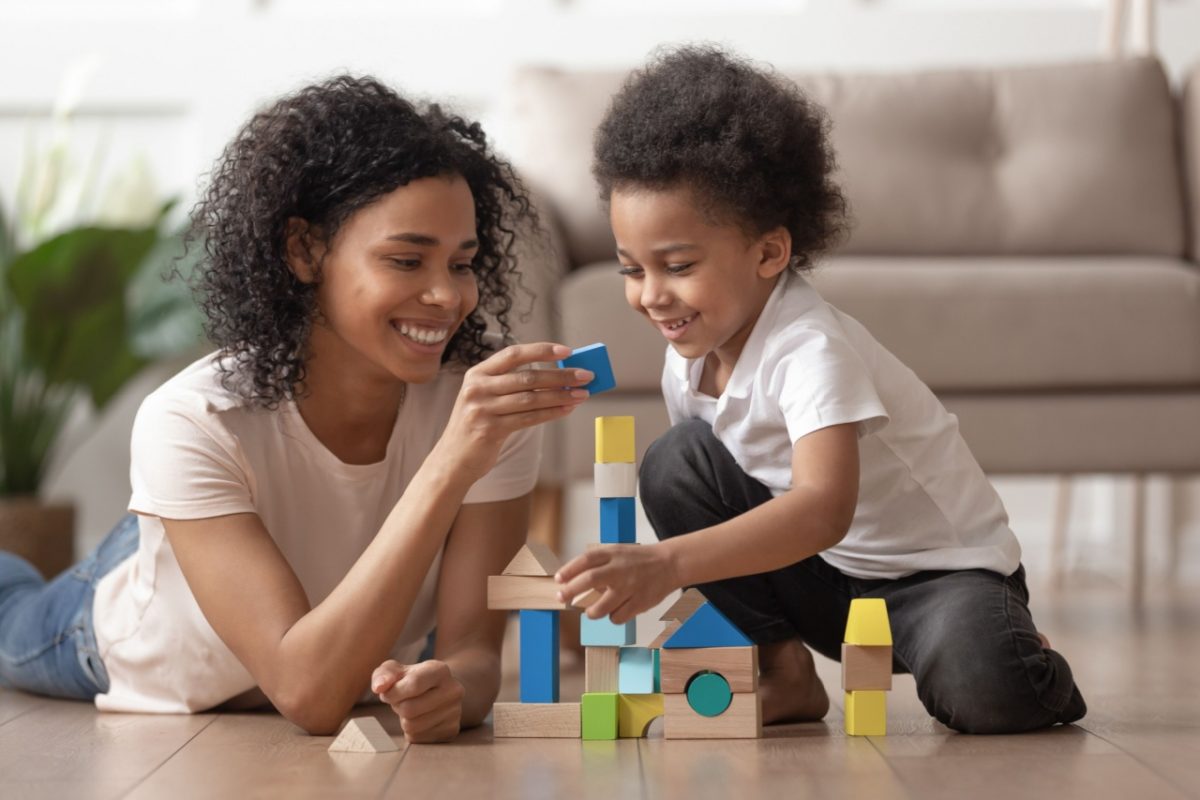 A mother and son building a tower from wooden blocks.