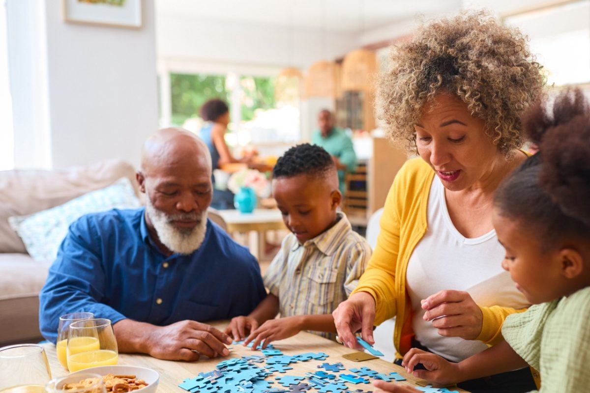 Grandparents doing a jigsaw with their two grandchildren.